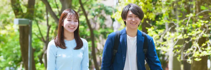 緑豊かな屋外を歩きながら談笑する社員2人