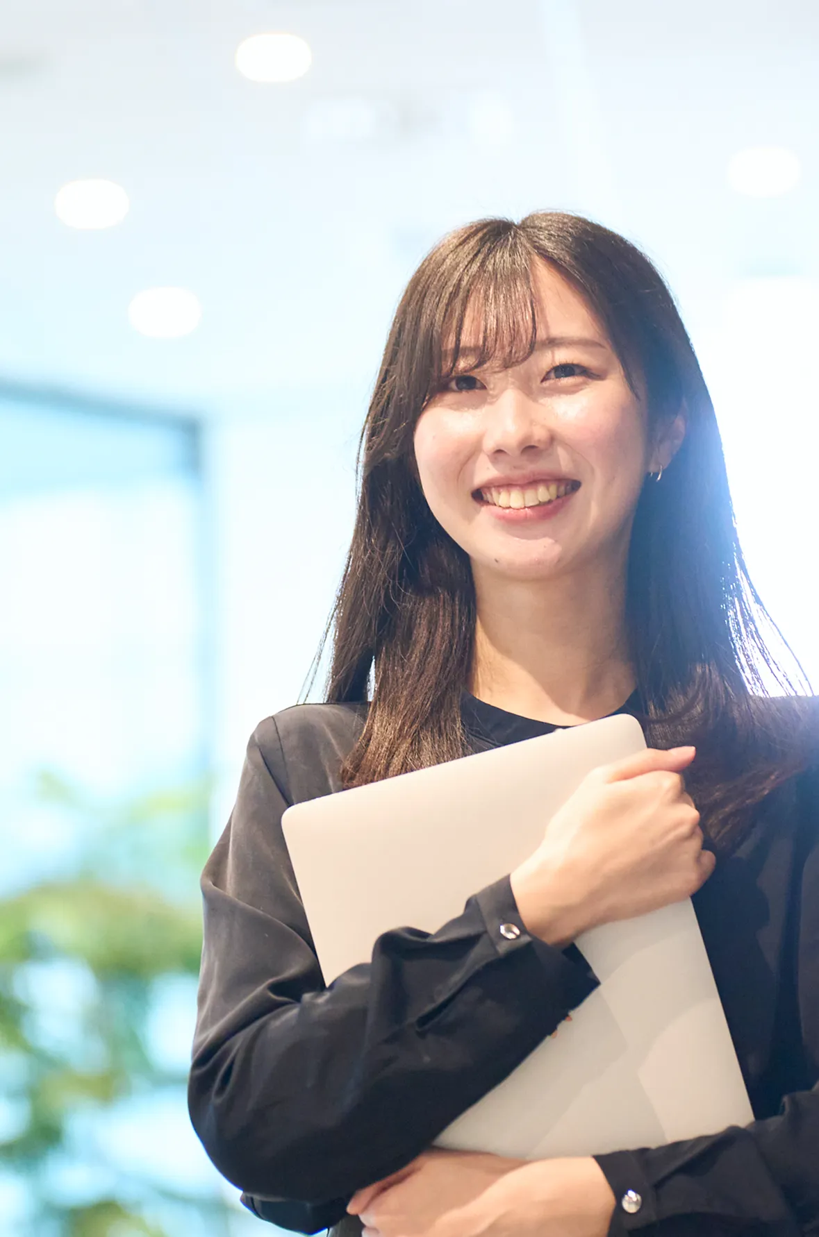 ノートパソコンを持ち微笑む女性社員